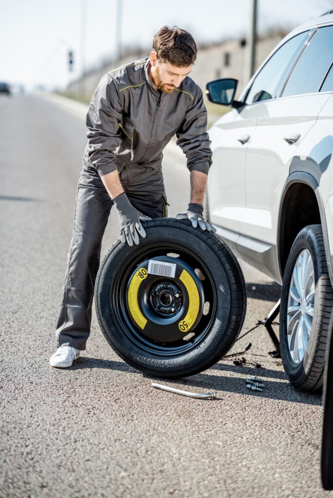 Worker changing car wheel on the road